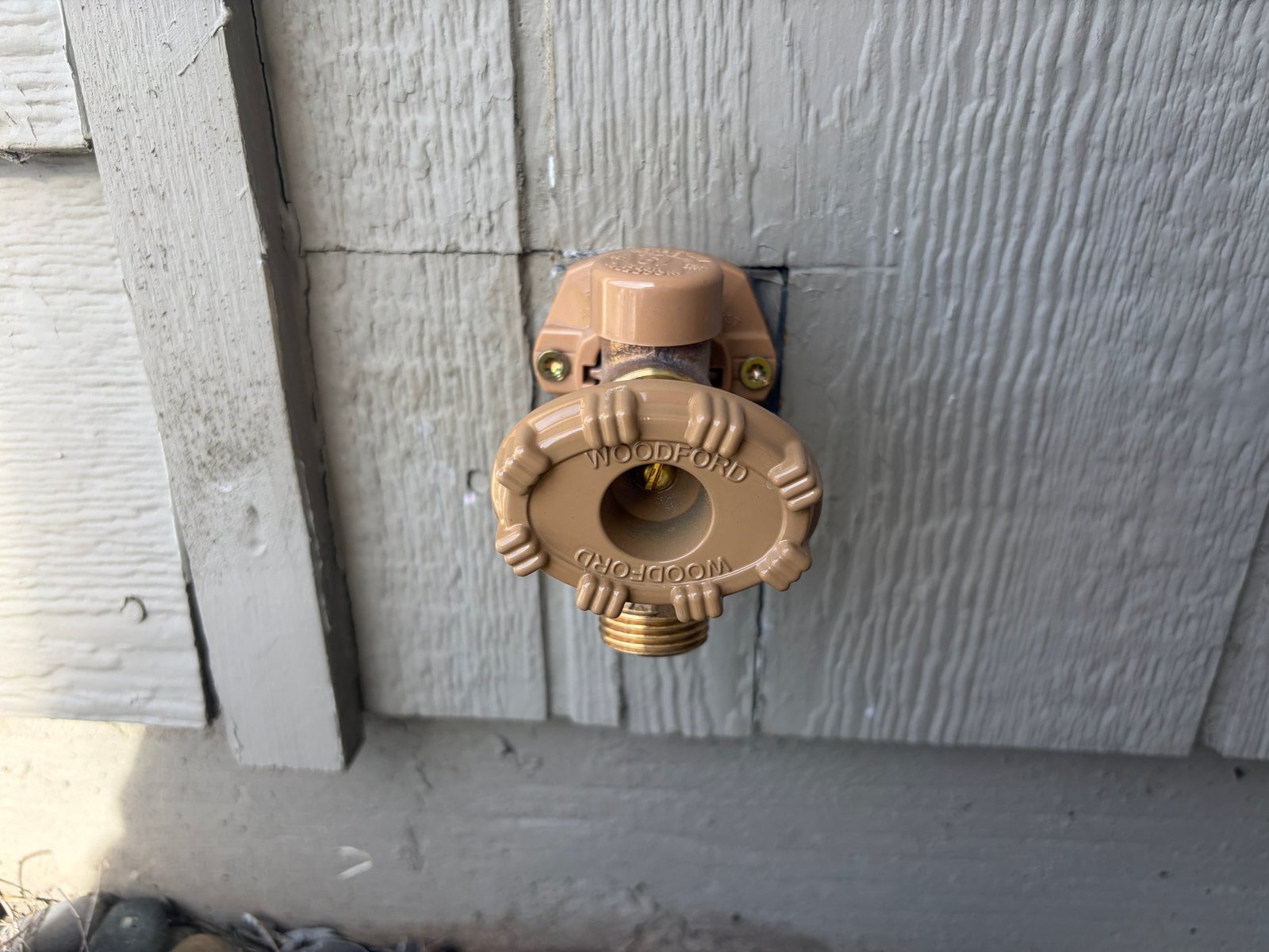 Newly installed Woodford Model 19 frost-free hose bib on the exterior wall of a Kennewick home, with the vacuum-breaker cap in place above the handle and a brass hose connection below it.