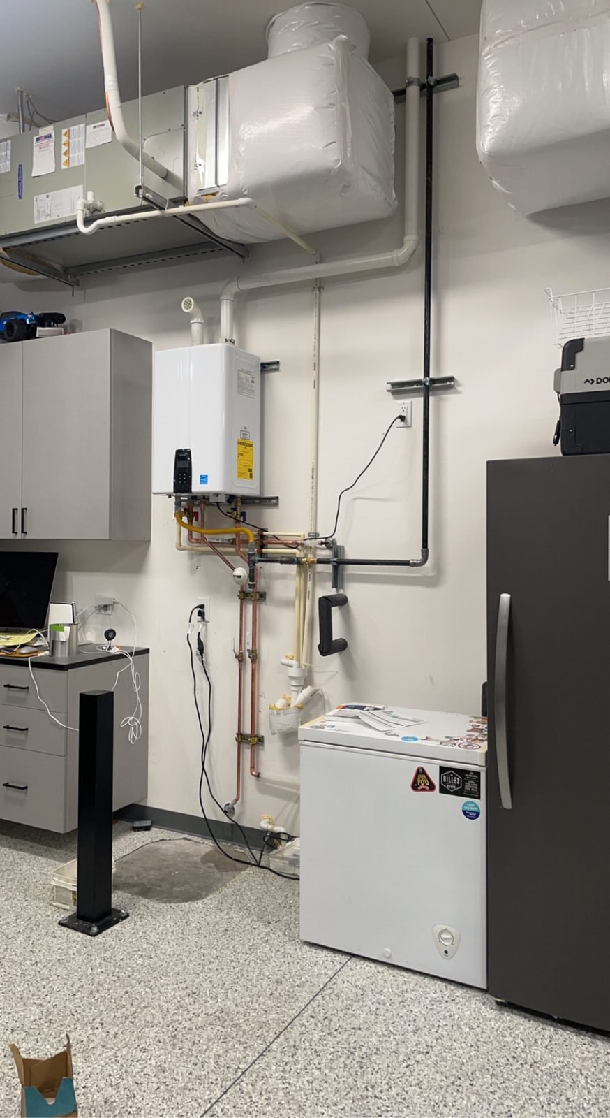 Wall-mounted tankless water heater installed in a Kennewick garage, with gas, water, and venting connections completed.